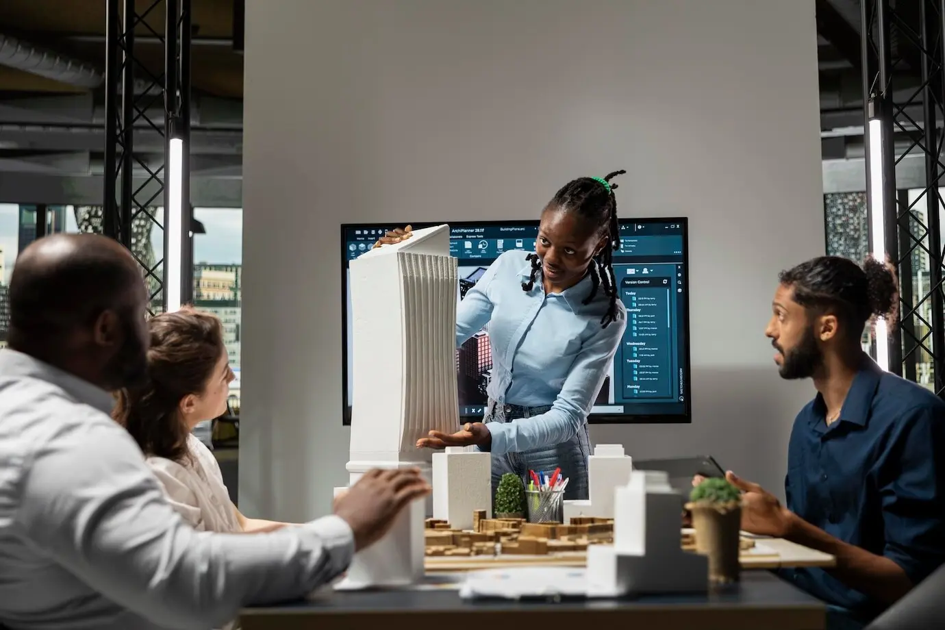 Appaltatrice afroamericana che presenta modelli architettonici 3D al suo team per rivedere le normative urbanistiche.